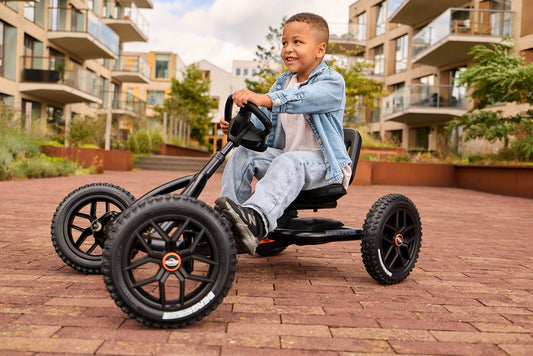 child riding BERG Buddy Cross Black pedal go kart outdoors enjoying active play Ireland