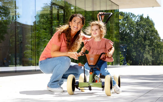 Child riding BERG Buzzy Retro Green 2-in-1 go-kart outdoors