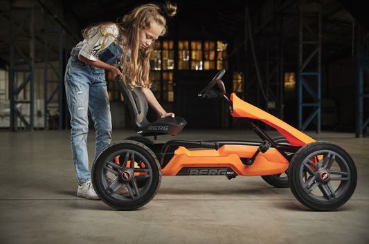 Child riding BERG Rally Orange pedal go-kart outdoors