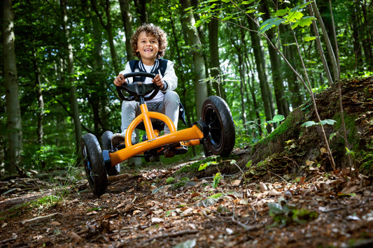 Child riding BERG Buddy B-Orange pedal go-kart outdoors