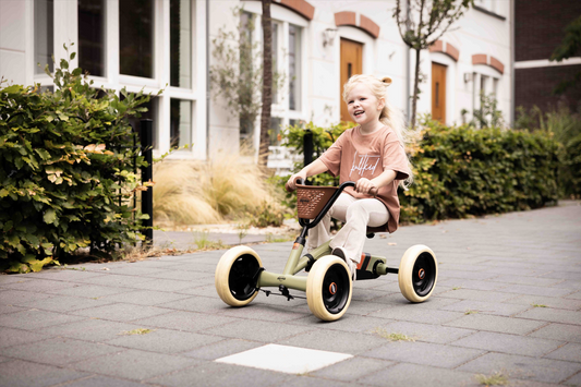 Child riding BERG Buzzy Retro Green pedal go-kart outdoors