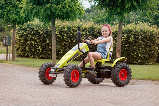 Child riding BERG Claas pedal tractor outdoors