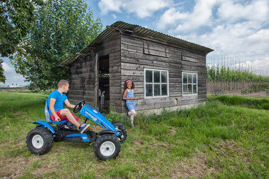 Child riding BERG New Holland pedal tractor outdoors