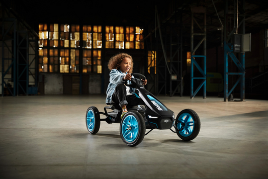 Child riding BERG Rally APX Blue pedal go-kart outdoors