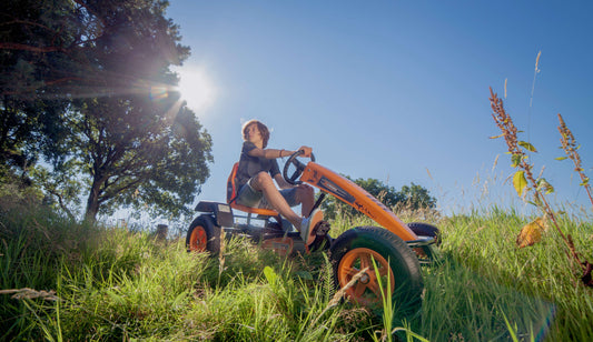 Child riding BERG X-Cross pedal go-kart outdoors