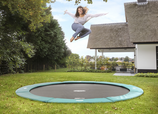 BERG FlatGround and InGround trampolines installed in a family garden showing different installation styles