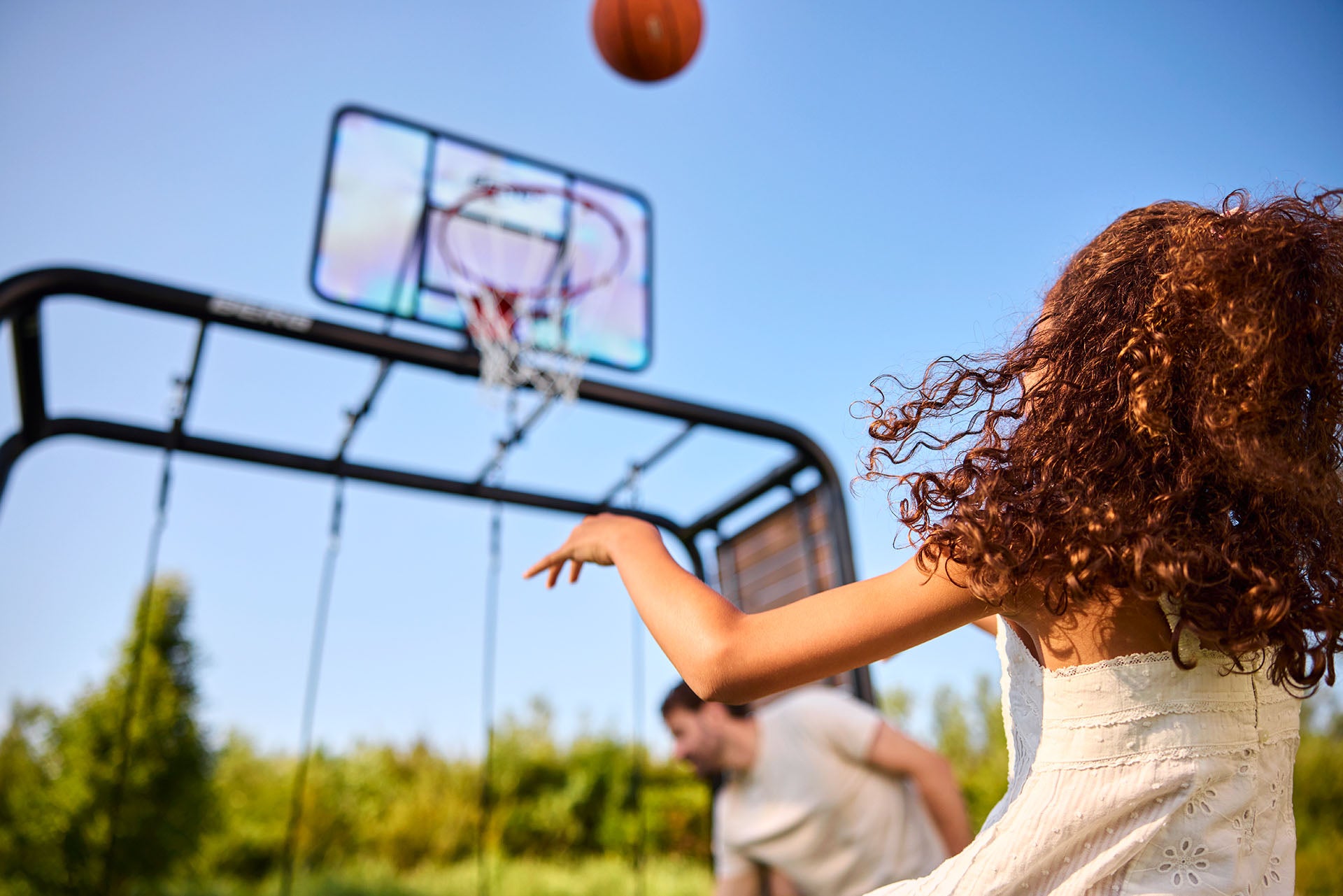 Person playing basketball outdoors with a clear blue sky