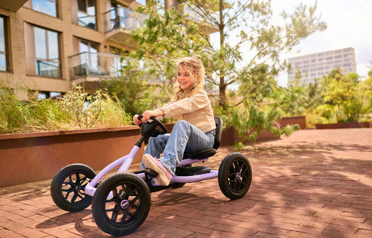 child riding BERG Buddy Purple pedal go kart outdoors enjoying active play Ireland