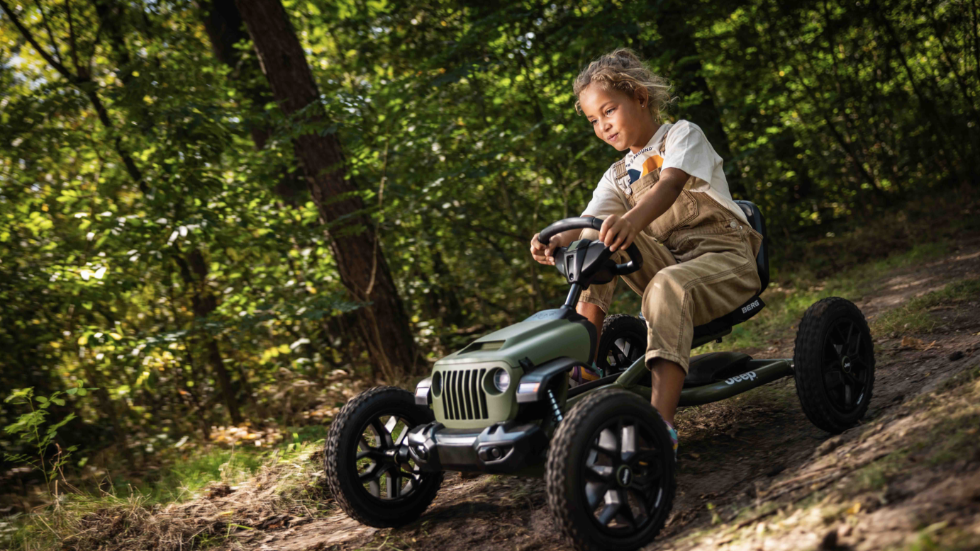 Child riding BERG Buddy Jeep Wrangler pedal go-kart outdoors
