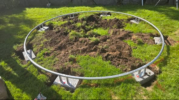 Marking the location layout for a Berg inground trampoline installation on a grass lawn