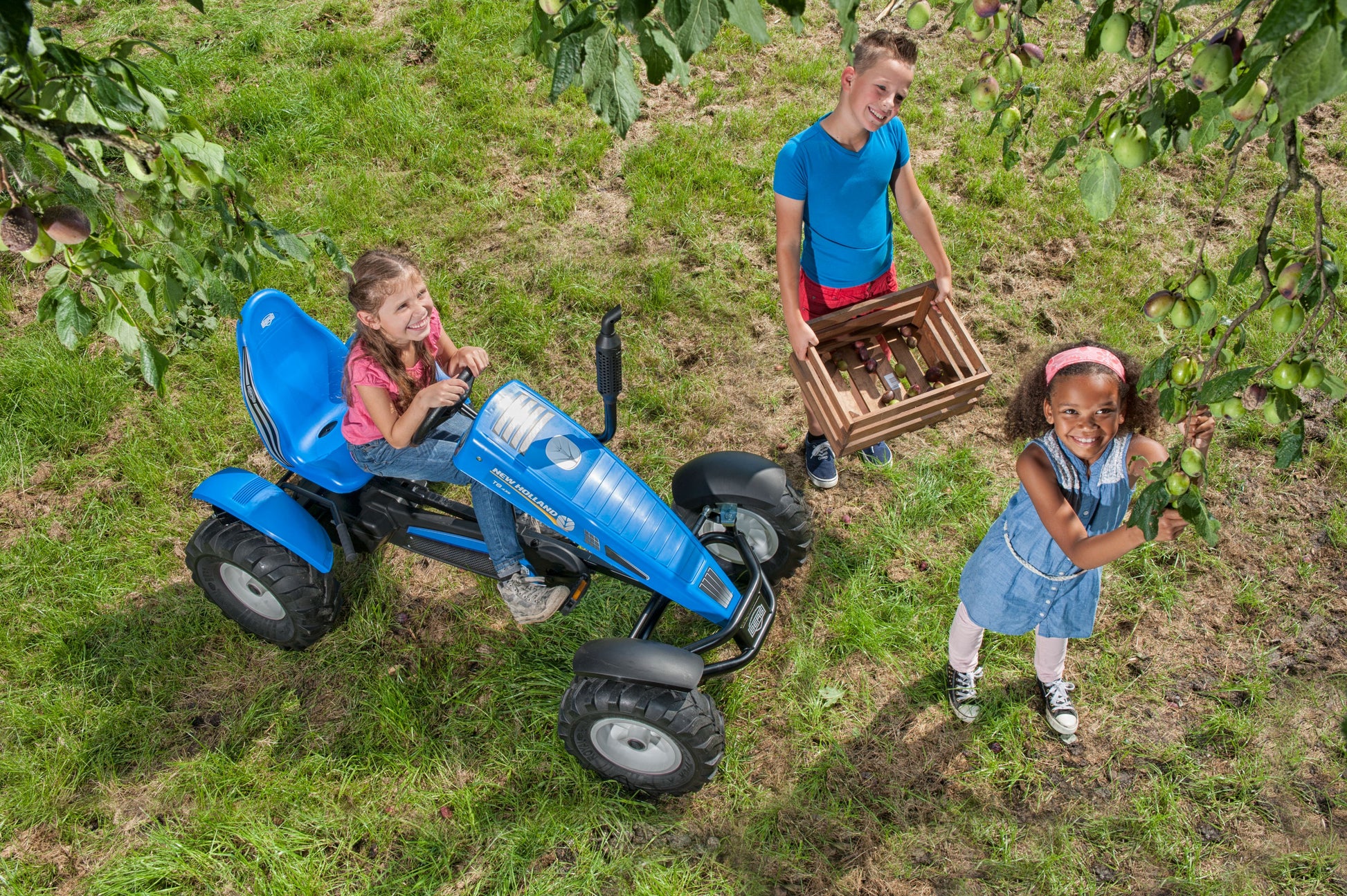 Child riding BERG New Holland pedal tractor outdoors