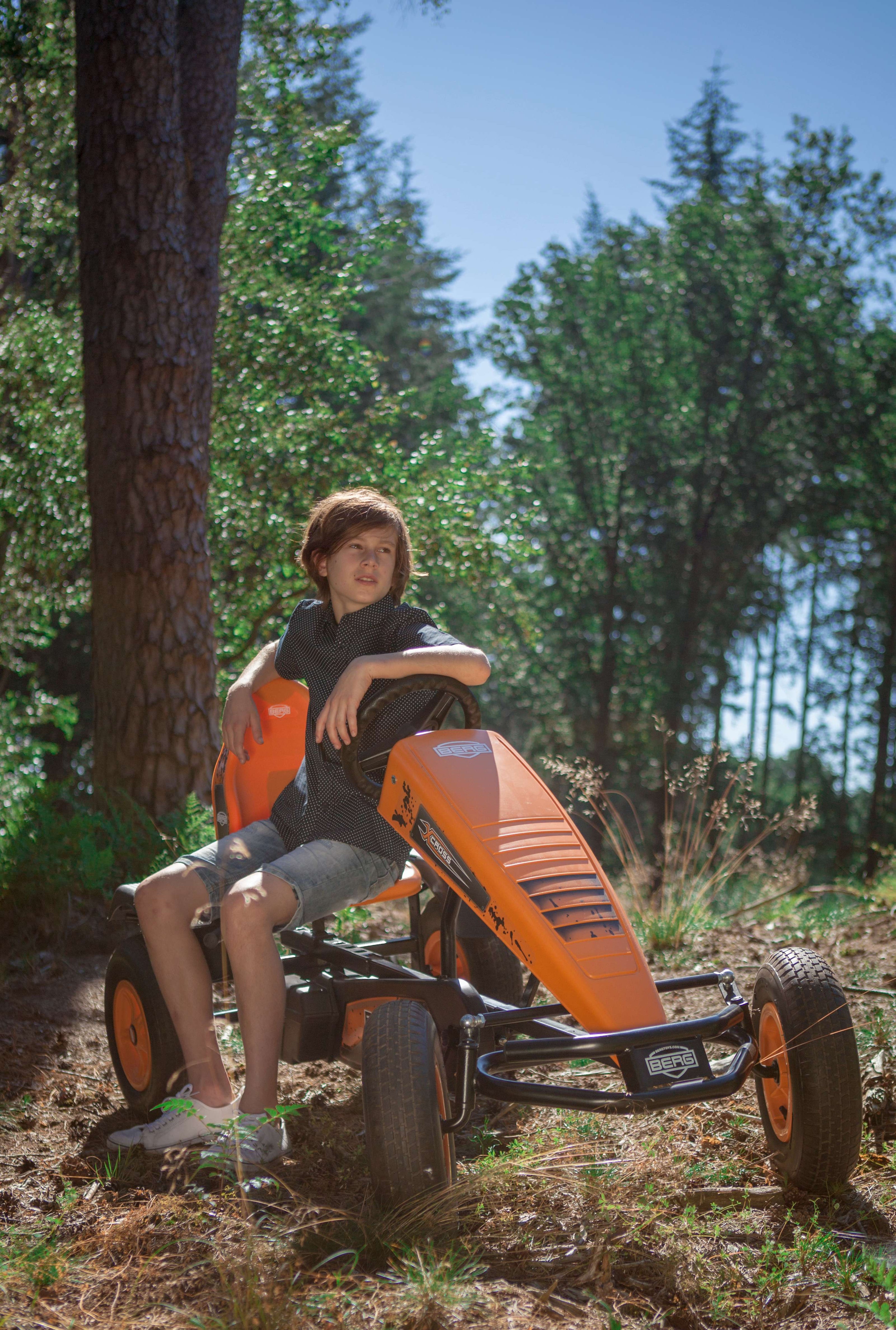 Child riding BERG X-Cross pedal go-kart outdoors