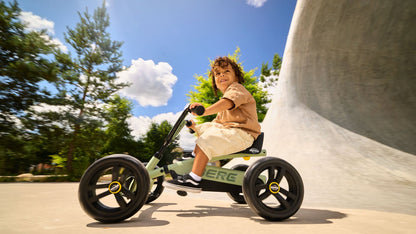 Happy kids using the BERG Buzzy Green ride-on pedal kart outdoors