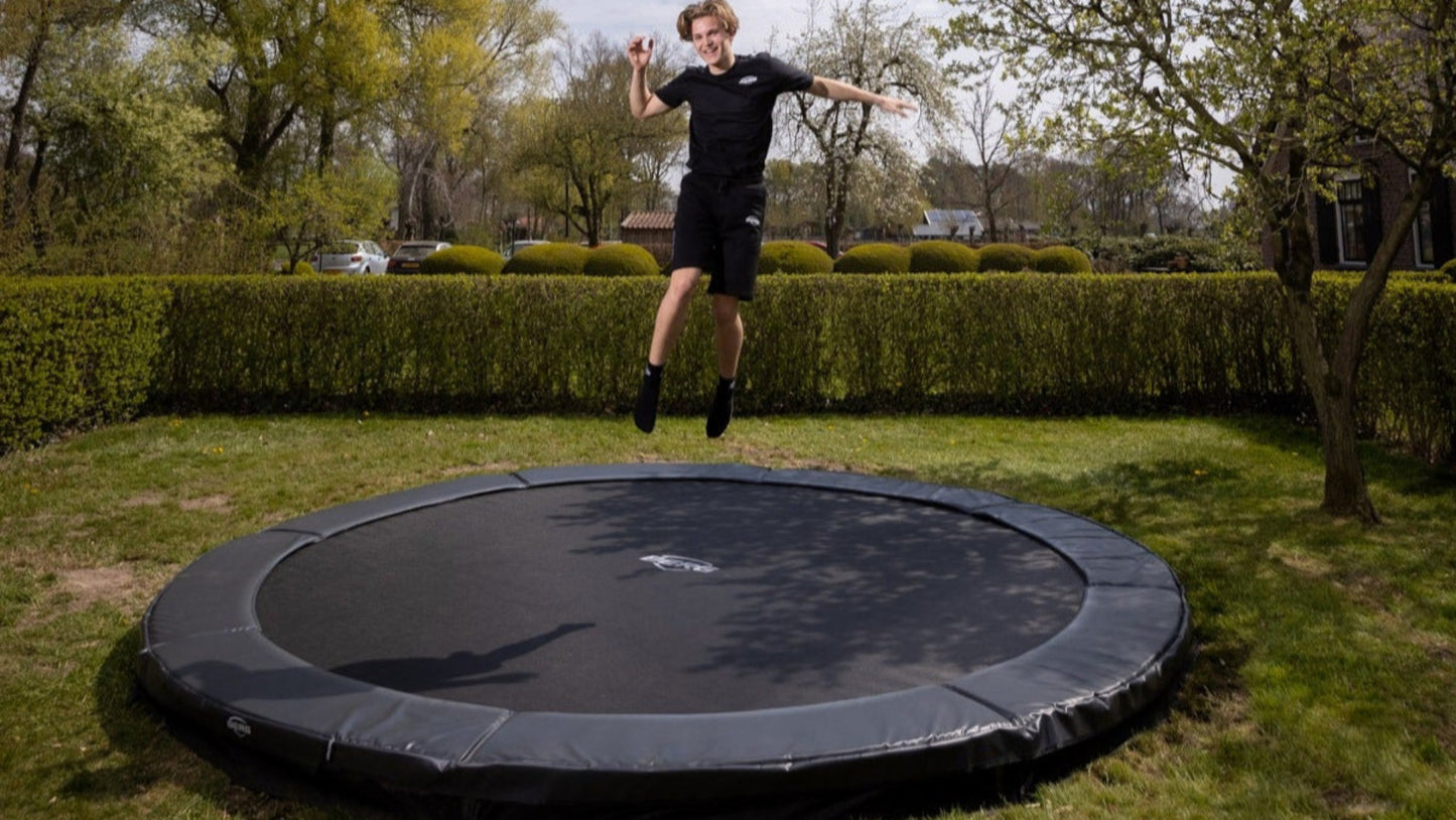 Child jumping on BERG Favorit InGround trampoline outdoors