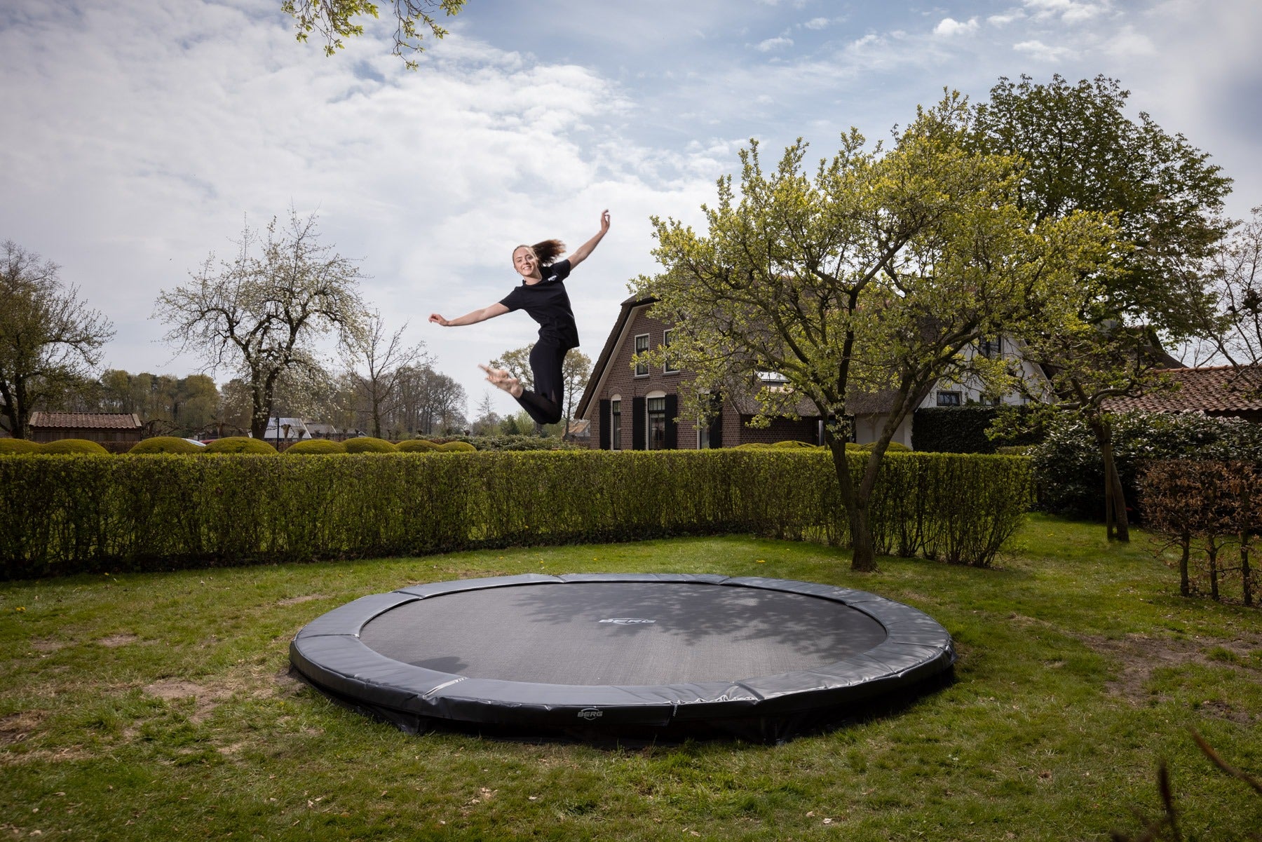 Child jumping on BERG Favorit InGround trampoline outdoors