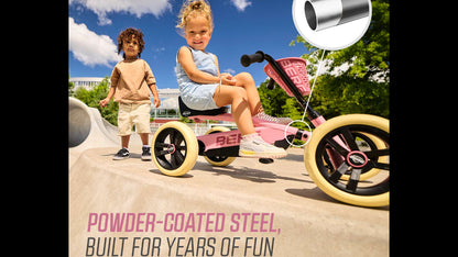 Toddler riding a pink BERG Buzzy pedal kart on a garden path